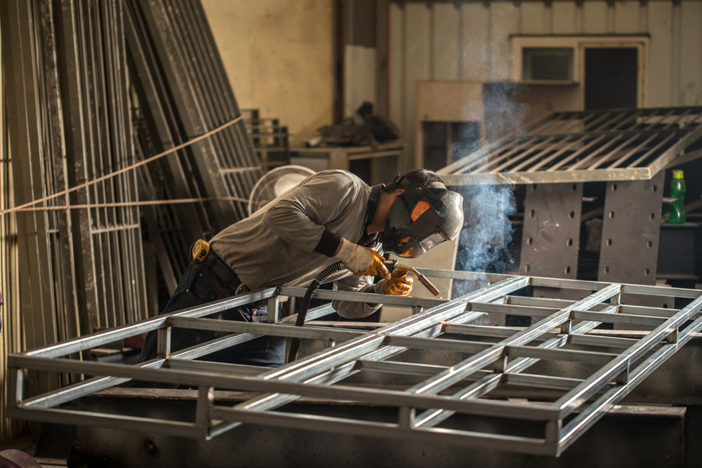 Industrial welder welding fabricated construction in factory. Welder working at the factory made metal and galvanized pipe.